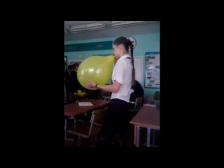 braided girl blow to pop yellow balloon in class