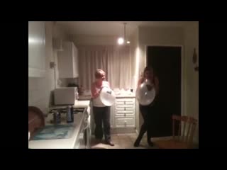 mom and daughter have a balloon race to see who pops first in the kitchen